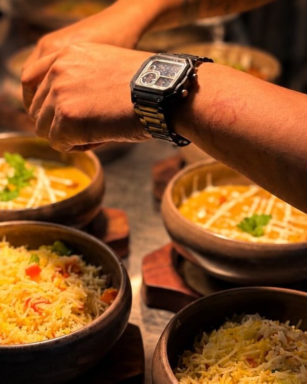 A cook's hands garnishing bowls of pulao and dal at the pass