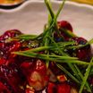 Chilli momos glazed in red sauce and topped with long chives
