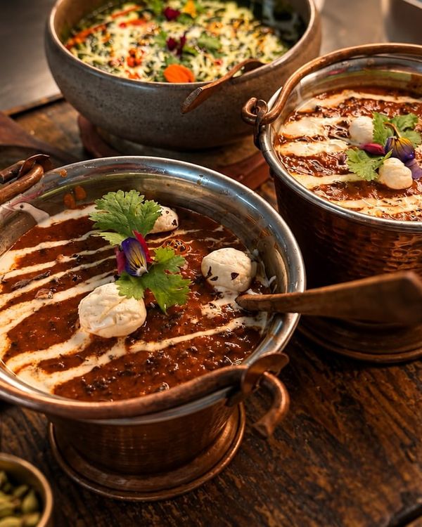 Two copper handis of curry swirled with cream
