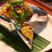 A wrapped kathi roll on a banana leaf, garnished with coriander