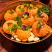 Pani puri in a brass bowl, garnished with herbs and edible flowers