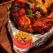 A steaming tandoori mixed grill platter on a wooden board