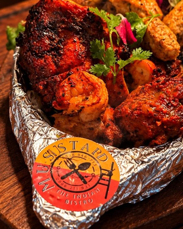 A tandoori mixed grill in foil on a wooden board